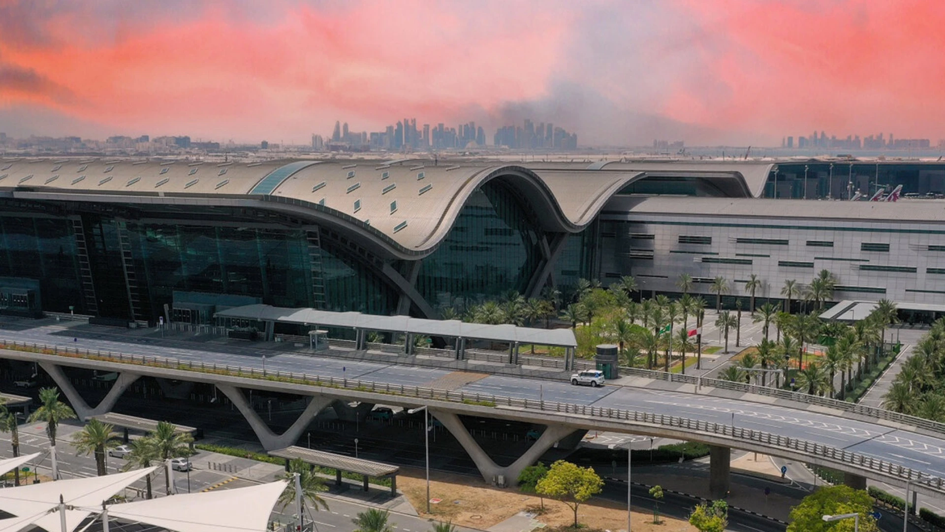 Hamad International Airport exterior at sunset with Doha skyline