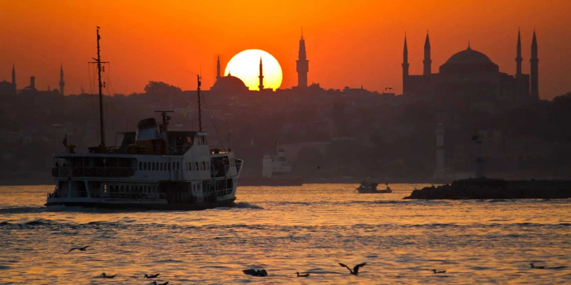 Bosphorus ferry at sunset with Istanbul skyline and minarets